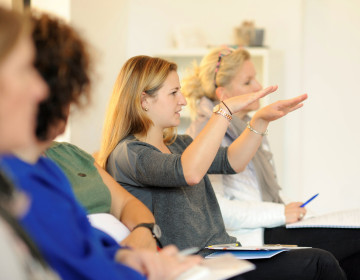 Teilnehmer*in erklärt gestikulierend eine Situation in der Weiterbildung zum Systemischen Deeskalationscoach